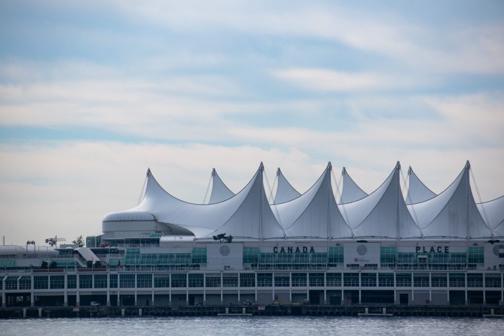 Iconic Canada Place building with its sail-like roof in Vancouver, BC against a blue sky.
